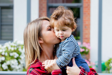 Young mother with a baby boy at outdoor near urban house in the city.