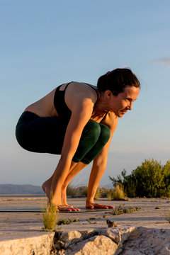 woman doing yoga on the top of a mountain during sunset