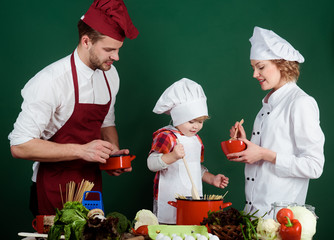 Family, food, culinary, cooking concept - happy family making dinner in kitchen. Child with parents cooking at kitchen. Family cooking kitchen food togetherness. Mum, dad&son preparing spaghetti meal.