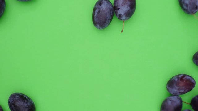 L&auml;ngliche frische reife Zwetschgen rollen in das Standbild. Sie decken den gr&uuml;nen Hintergrund ab, der f&uuml;r chroma keying geeignet ist. Aufnahme in Echtzeit von oben.