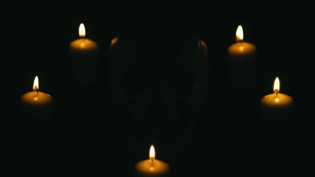 Skull between candles, halloween theme, with spot lights on and off