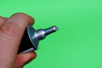 open iron tube of glue in hand on a green background