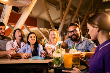 Beautiful waitress carries a tray of drinks for visitors to the bar