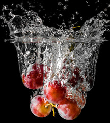 A cluster of grapes dopped into liquid creating beautiful splash