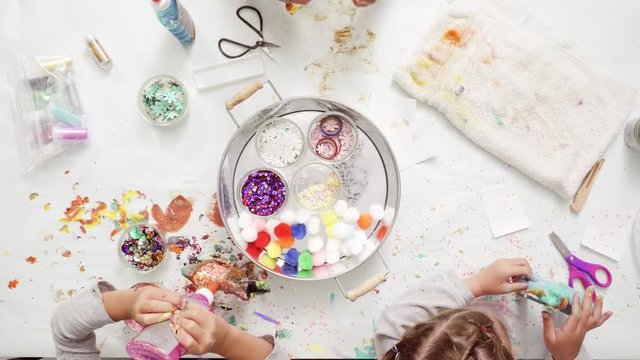 Step by step. Little girls decorating paper mache unicorn with glitter and paper flowers
