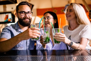 Three cheerful friends clink glasses in the bar