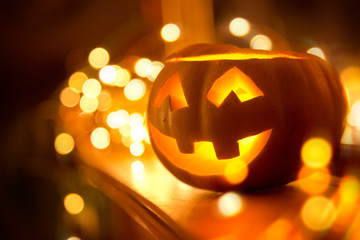 A cheerful smiling Jack O Lantern on halloween placed on a fireplace with fairy lights