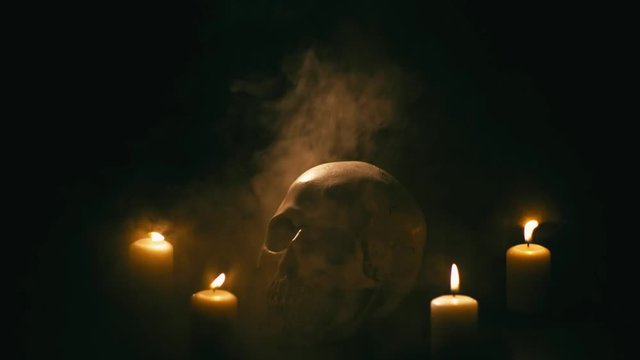 Skull between candles with smoke, halloween theme