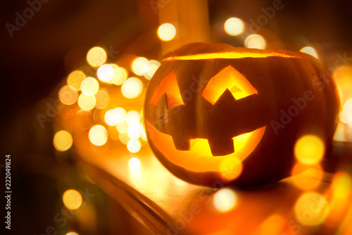 A cheerful smiling Jack O Lantern on halloween placed on a fireplace with fairy lights