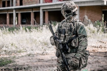 Peacemaker in a helmet and balaclava, holding an assault rifle in his hands. The concept of war