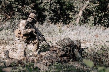 Military soldiers in the war masked in the grass taking a fighting position for shooting