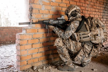 Airsoft gun took a fighting position for shooting in a destroyed building