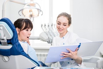 Obraz premium Dentist in white uniform shows the results of the examination to the client in the dental clinic