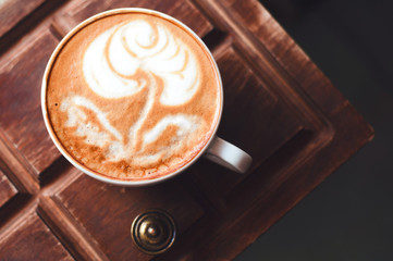 Top view of hot coffee cappuccino latte art in white ceramic cup on wooden plate. Coffee cup top view on old wooden. Coffee cup in coffee shop