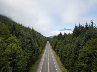 Fototapeta premium Aerial view of a scenic road in the Canadian Landscape during a vibrant cloudy summer day. Taken in Northern Vancouver Island, BC, Canada.