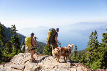 Man, woman and dog are hiking during a vibrant summer sunset. Taken in Howe Sound, near Vancouver,...