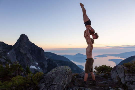 Man and Woman doing acroyoga on top of a mountain during a vibrant summer sunset. Taken in Howe Sound, near Vancouver, BC, Canada.