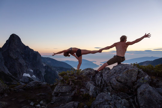 Man and Woman doing acroyoga on top of a mountain during a vibrant summer sunset. Taken in Howe Sound, near Vancouver, BC, Canada.