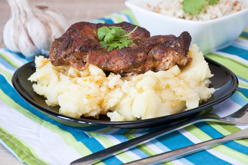 Roasted pork neck with potatoes decorated with coriander leaf