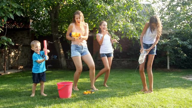 4k video of happy young family having water guns battle at hot sunny day on grass
