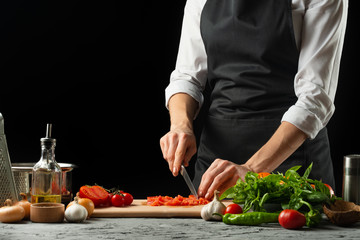 The chef cuts and tastes tomatoes, preparing an Italian tomato sauce for macaroni.pizza. The concept of the Italian cooking recipe