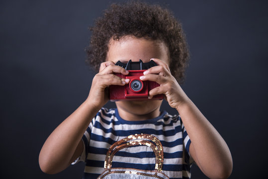 Cute little african american girl using a toy camera to take pictures