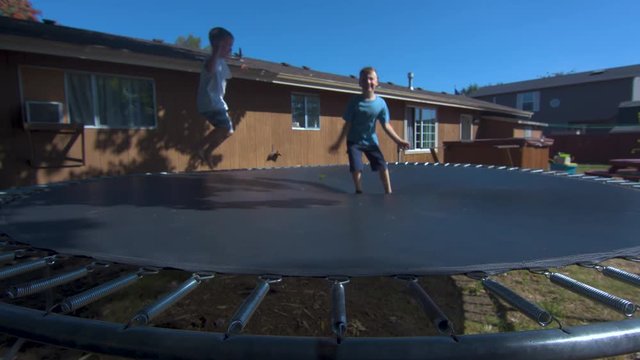 Wide Shot of Two Boys Jumping on a Trampoline in Slow Motion
