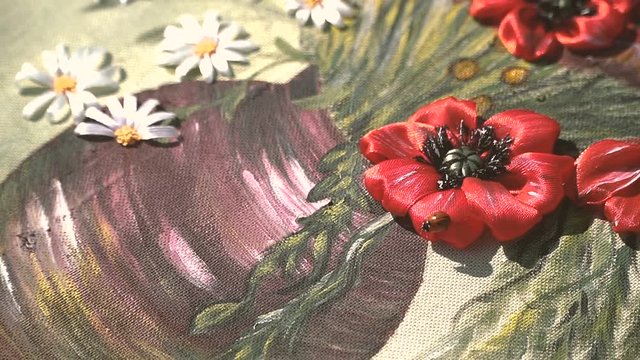 Embroidery with ribbon. A ladybird crawls on the picture
