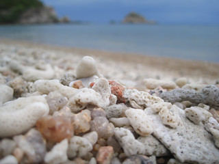 Obraz na płótnie Canvas Closeup pebble with blurred sand beach, island, sea and blue sky in background