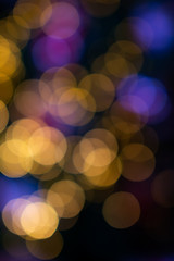 Abstract blurred circular yellow and purple light bokeh with dark background