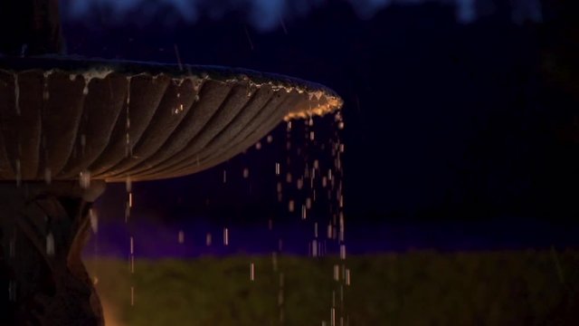 Drops of water on a fountain during night with fire light