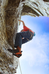 male rock climber on the cliff against a blue sky