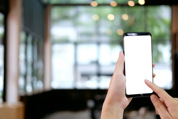 Cropped shot hands touching mockup smartphone on cafe background.