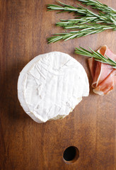 cheese brie and prosciutto jamon ham wooden background rosemary