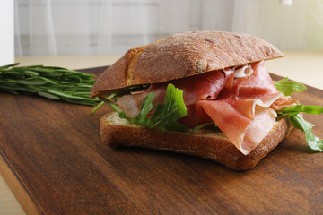 sandwich with prosciutto jamon on a wooden background