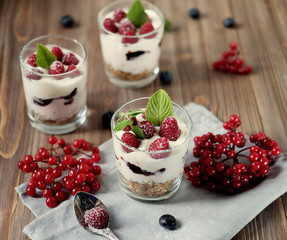 Healthy breakfast - yogurt with fresh berries and muesli served in glass jar, on wooden background