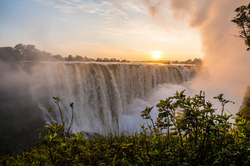 Victoria Falls at sunrise. Observing the power of the water falls.  - obrazy, fototapety, plakaty