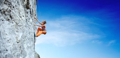 Fototapeten young slim woman rock climber climbing on the cliff © vitaliymateha