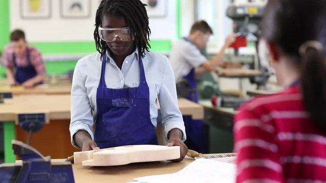 Female High School Student Building Guitar In Woodwork Lesson