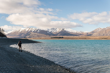 Fototapeta na wymiar Man taking a photo of mountains at Lake Tekapo