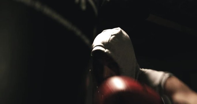 Boxer punching bag with red gloves in dark environment