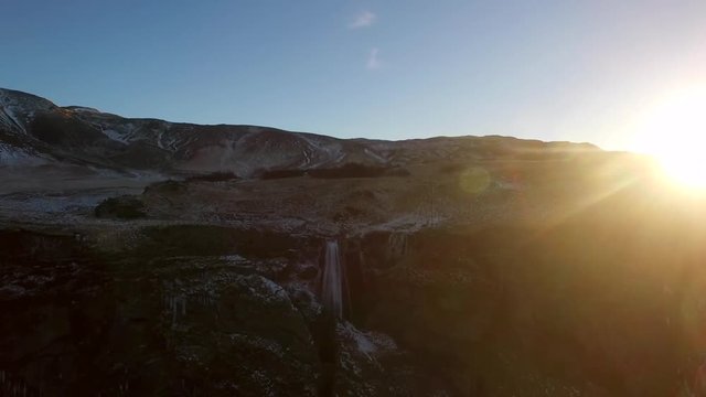 Ultra wide fly away aerial shot of Icelandic Waterfall Wide aerial shot flying towards and over Icelandic Waterfall Glj&radic;&int;frab&radic;&int;i with huge lens flare from setting sun
