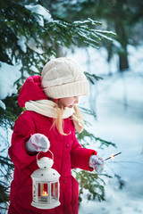 Little girl with a flashlight and Bengal lights. Forest, winter day
