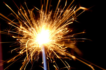 Firework background / A sparkler is a type of hand-held firework that burns slowly while emitting colored flames, sparks, and other effects