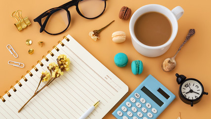 Woman work desk with macaroon, flower, calculator, notebook and coffee cup