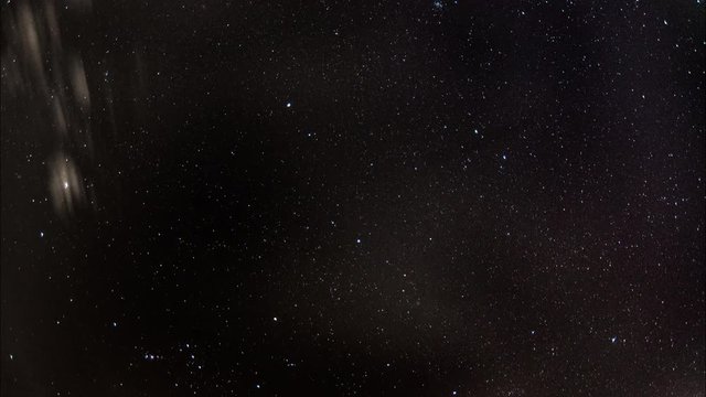 Abstract perspective of a star trail timelapse as the stars rotate across the night sky and blurred clouds pass by over time.