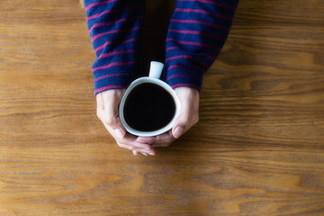 Woman is hands holding cup coffee, top view, wood