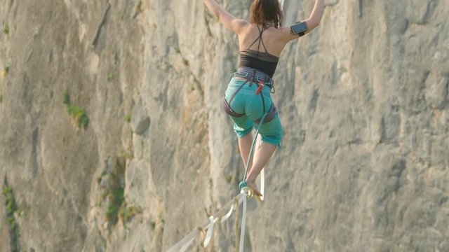 Athlete balancing on high line slack line over cliff in high mountains at sunset