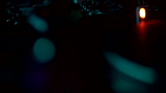 The camera moves up revealing a DJ equipment and spinning record in the background. Slow motion, dark environment.