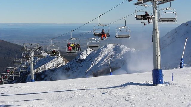 A Day at the snow with the chairlift moving as the Australian Alps are in the background .